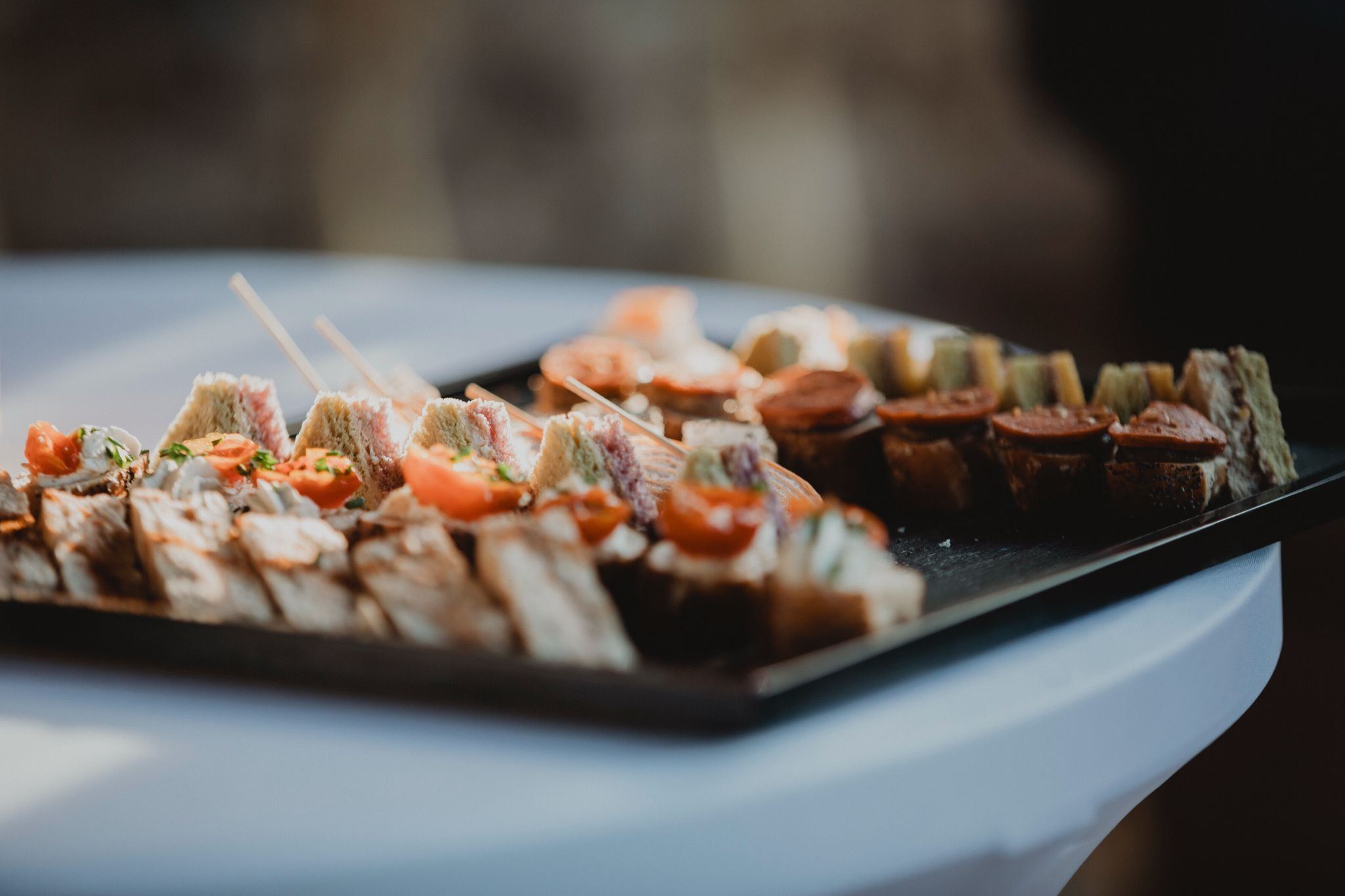Plateau de canapés du cocktail, mini-sandwichs et toasts, sur une nappe blanche