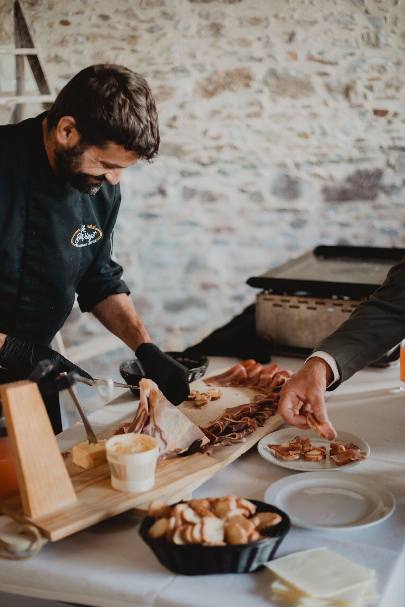 Le chef, souriant, tranche du jambon sur le buffet d’une réception