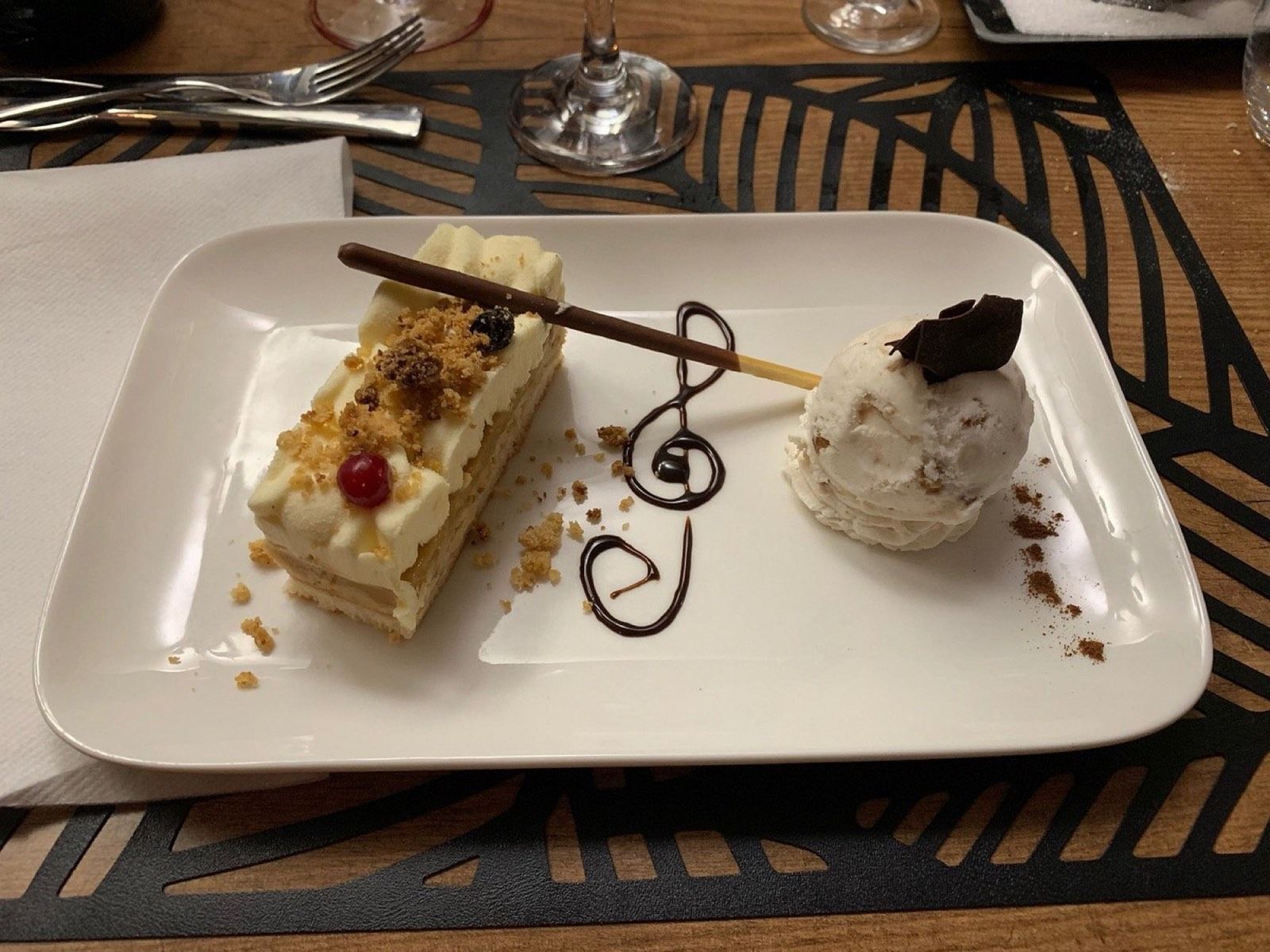 Dessert à l’assiette : pâtisserie crémeuse en fines couches, boule de glace et clé de sol dessinée au chocolat